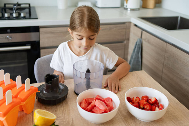 Portrait of cute child girl making ice cream. Kid have fun making with homemade fruit puree ice cream. Home made ice lollies. High quality photo - 写真・画像