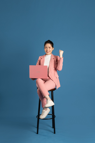 Portrét mladé podnikatelky sedící v křesle a izolované na modrém pozadí - Fotografie, Obrázek