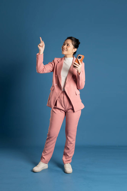 Портрет молодої бізнес-леді, що стоїть і позує ізольовано на синьому фоні - Фото, зображення