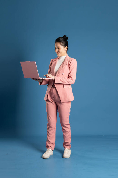 Портрет молодої бізнес-леді, що стоїть і позує ізольовано на синьому фоні - Фото, зображення