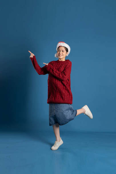 Kaunis nainen yllään Santa hattu eristetty sininen seinä - Valokuva, kuva