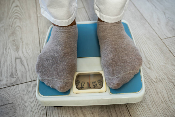 Close-up of woman's feet in socks standing on a bathroom scale. Measuring body weight - Photo, Image