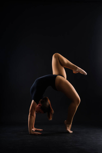 Turnen, Akrobatin, Turnerin mit starkem, flexiblen Körper über schwarzem und weißem Hintergrund - Foto, Bild