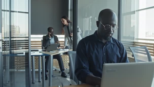 Медленный снимок мужчины, работающего над ноутбуком, и женщины-коллеги, приносящие отчет директору, говорящему по телефону в офисе - Кадры, видео