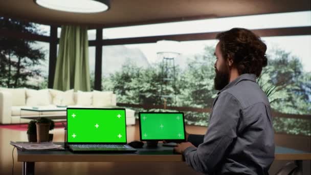Empresario que usa pantallas de pantalla verde en dispositivos, sentado en su escritorio en una lujosa villa en un bosque. Empresario rico mirando las pantallas que muestran el copyspace aislado, trabaja en el ordenador portátil y la tableta. - Imágenes, Vídeo