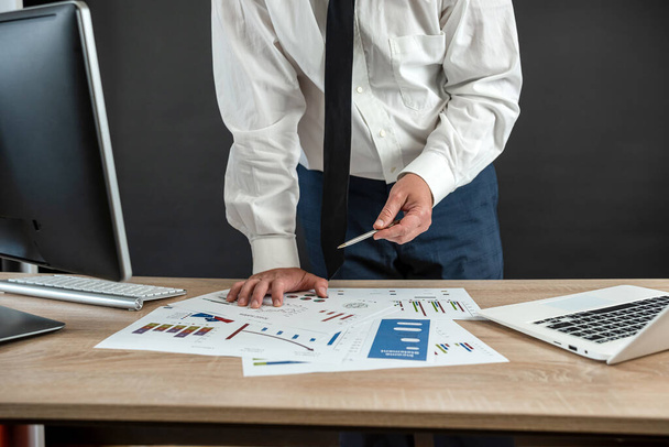  Un uomo d'affari caucasico in giacca e cravatta lavora con un grafico aziendale in ufficio. Concetto finanziario - Foto, immagini