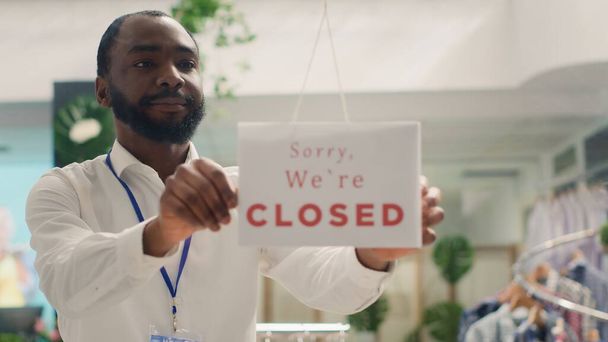 BIPOC 'taki adam şık bir moda mağazasında stok yapmak için dükkanı kapatıyor. Afro-amerikan çalışanlar mağazanın kapısına "kapalı" tabelası ekleyerek, yeni koleksiyon ekleyerek - Fotoğraf, Görsel
