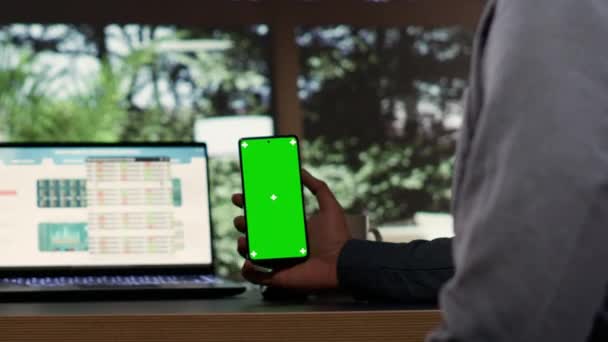 Male billionaire uses greenscreen phone display at desk in his opulent alpine retreat, rich entrepreneur at vacation home. Young shareholder works with isolated chromakey, investing capital funds. - Footage, Video
