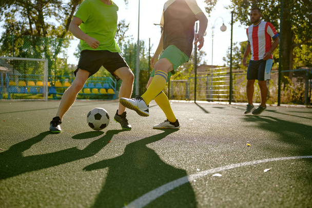 Magabiztos focisták labdáznak a városi utcai focipályán. Férfi legjobb barátok aktív kikapcsolódás és közös hobbi - Fotó, kép