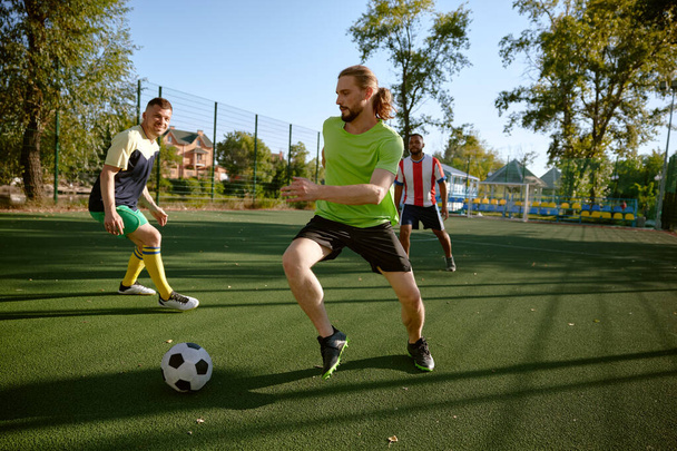 Sportoló csapat focizik a pályán élvezi az aktív időt a vidéken. Férfi hobbi, versenyképes sport játék - Fotó, kép
