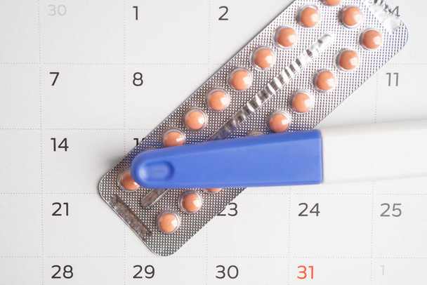 Terhességi teszt és fogamzásgátló tabletták a naptárban, fogamzásgátlás egészség és gyógyszer. - Fotó, kép