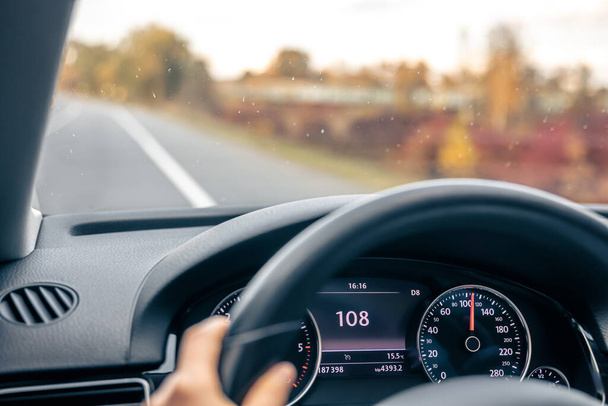 Οδήγηση στην εθνική οδό φαίνεται από τα μάτια της γυναίκας, τιμόνι σε ένα αυτοκίνητο γκρο πλαν, υψηλής ταχύτητας οδήγηση στο δρόμο, αντίγραφο χώρο. - Φωτογραφία, εικόνα