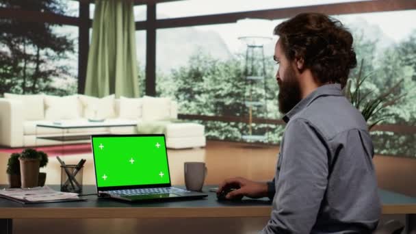 Billionaire stakeholder unwinds in front of greenscreen display on his laptop, exquisite mountain lodge. In a successful business functioning, foreign manager operates with blank mockup screen on pc. - Footage, Video
