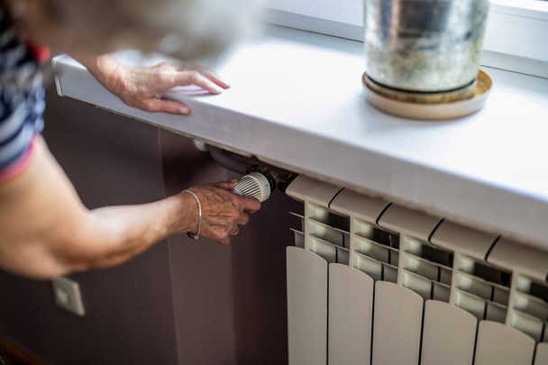 Femme âgée vérifiant la température sur un radiateur de chauffage dans la cuisine à la maison - Photo, image