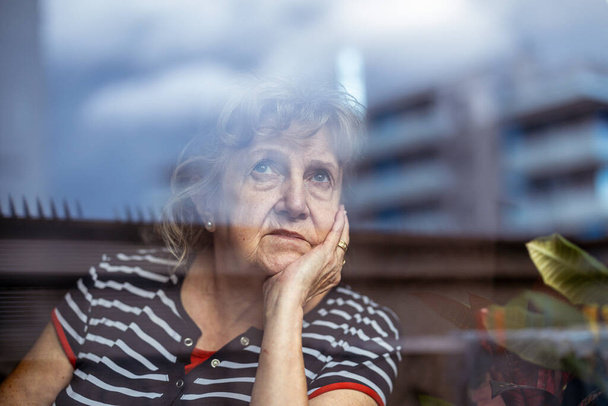 Ritratto di donna anziana che guarda attraverso la finestra
  - Foto, immagini