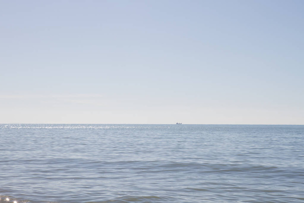 Barco navegando a la distancia en un paisaje marino con colores naturales - Foto, imagen