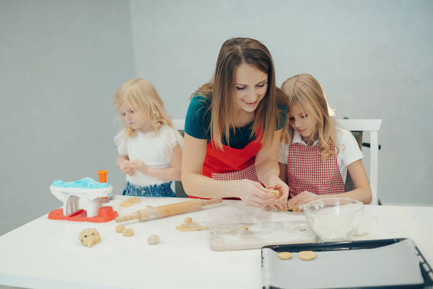 Μητέρα και κόρες φτιάχνουν μπισκότα στην κουζίνα και διασκεδάζουν στο σπίτι - Φωτογραφία, εικόνα