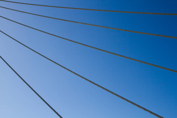 Натянутые веревки в ряд равномерно против голубого неба - Фото, изображение