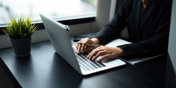 Крупним планом Азіатська ділова жінка використовує ноутбук для розрахунку податкових та фінансових даних бізнесу в офісі. - Фото, зображення