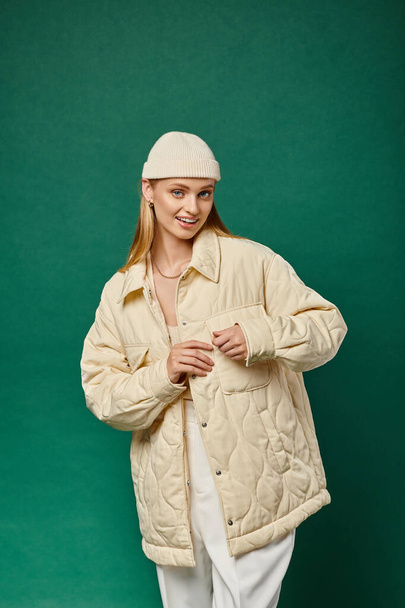 Sıcak ceketli ve şık bereli bir kadın yeşil kameraya bakıyor, kış modası trendi. - Fotoğraf, Görsel