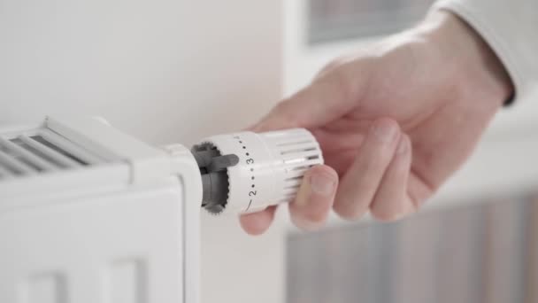 O homem reduz o poder de aquecimento da casa a partir do valor máximo para o modo econômico, girando a válvula do termostato do radiador, e abre a janela ligeiramente para deixar entrar ar fresco. - Filmagem, Vídeo