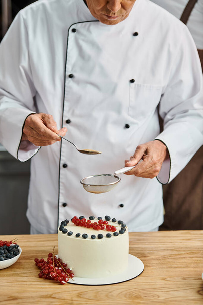 καλλιεργημένη άποψη του ώριμου σεφ διακόσμηση νόστιμα γλυκό κέικ του με καφέ ζάχαρη, μαθήματα μαγειρικής - Φωτογραφία, εικόνα
