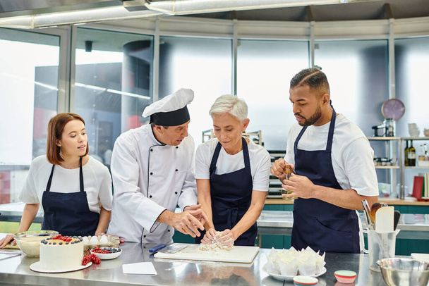 guapo cocinero jefe maduro ayudar a sus chefs multiculturales con pasteles, confitería - Foto, imagen
