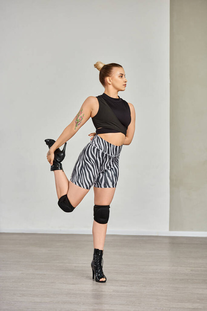 mujer con gracia estira la pierna en pantalones cortos de cebra y tacones altos, mostrando equilibrio y flexibilidad - Foto, imagen