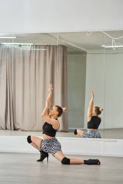 Een sierlijke danseres op hoge hakken vindt evenwicht en kracht in haar choreografie tegen een muur - Foto, afbeelding