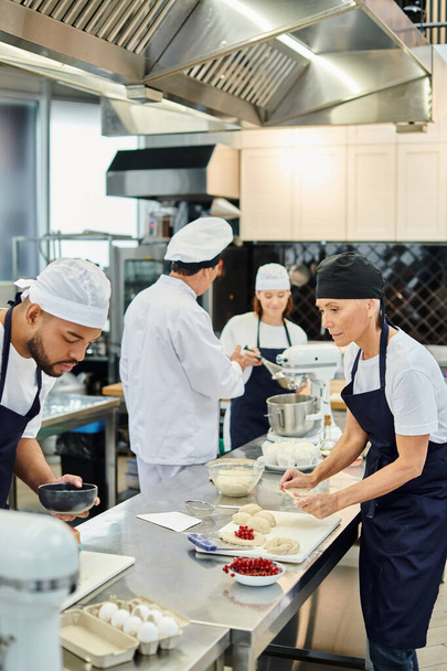 focussen op diverse chef-koks in schorten die werken aan gebak naast hun wazige collega en chef-kok - Foto, afbeelding