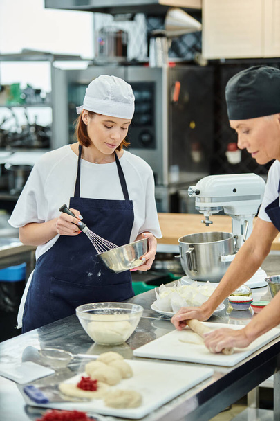 belas chefs do sexo feminino em toques azuis e aventais trabalhando em sua massa juntos, confeitaria - Foto, Imagem
