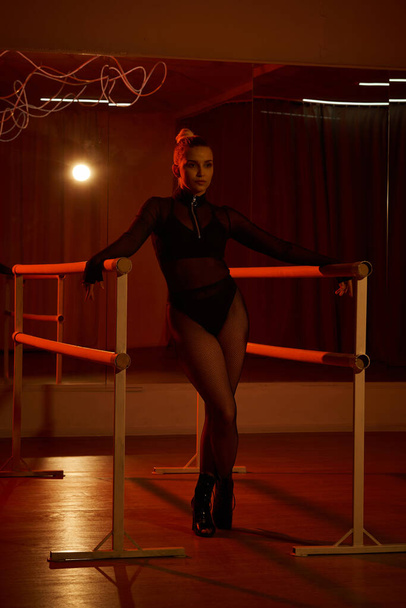 грациозная танцовщица демонстрирует идеальный баланс, когда она бьет позу на полу, завораживая хореографией - Фото, изображение