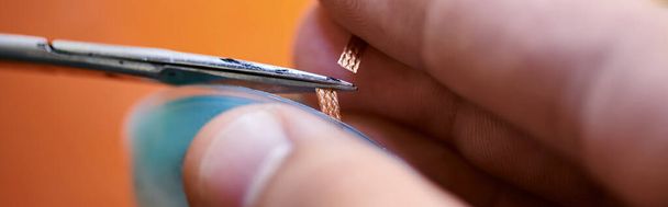 Tamir atölyesi ve afişte elektronik aletin kablosunu kesen deneyimli teknisyenin kısmi görüntüsü - Fotoğraf, Görsel