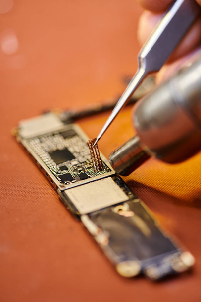 vista ritagliata del chipset di saldatura riparatore di gadget elettronico in officina, piccola impresa - Foto, immagini