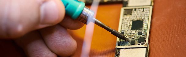 обрезанный вид квалифицированного техника пайки электронных чипсетов в ремонтной мастерской, горизонтальный баннер - Фото, изображение