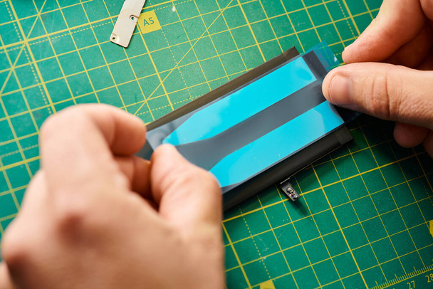 vue recadrée du réparateur professionnel testant la batterie de téléphone portable dans l'atelier, petite entreprise - Photo, image