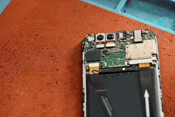 vista superior do celular quebrado desmontado na mesa na oficina moderna, negócio de reparação de equipamentos - Foto, Imagem