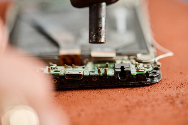 close up view of disassembled broken mobile phone on table during maintenance in workshop - Foto, Imagem