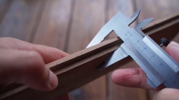 De dikte van een houten stuk wordt gemeten met een schuifmaat, close-up. Nauwkeurige pasvorm en grootte check. Hoge kwaliteit 4k beeldmateriaal - Video