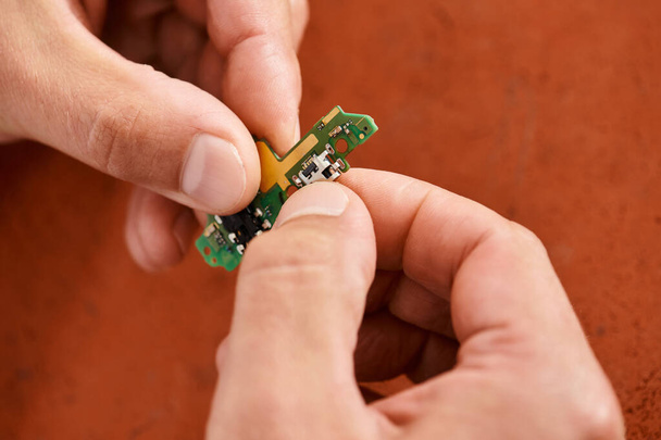 close-up zicht op handen van professionele technicus met elektronische chipset in reparatiewerkplaats - Foto, afbeelding