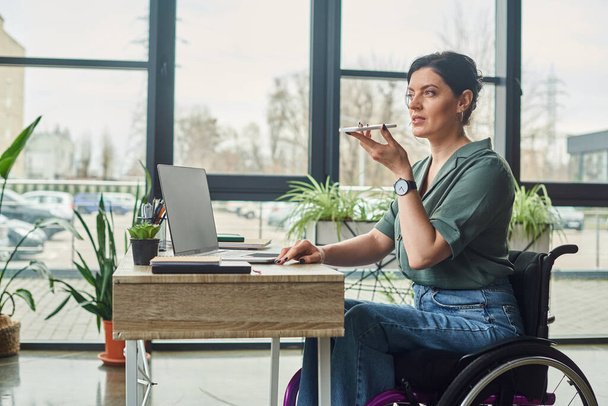 tekerlekli sandalyedeki engelli bir iş kadını telefonuyla sesli mesaj kaydediyor. - Fotoğraf, Görsel