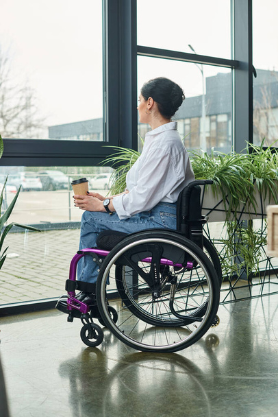 attraktive engagierte behinderte Frau in Freizeitkleidung im Rollstuhl mit Kaffee im Büro - Foto, Bild