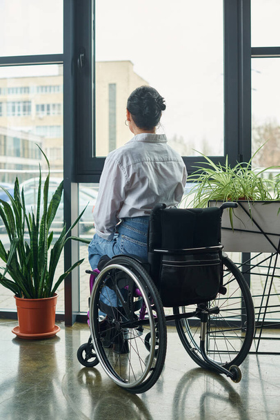 donna d'affari dedicata con disabilità seduta sulla sedia a rotelle mentre lavora duramente in ufficio - Foto, immagini