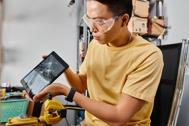 profesionální asijský opravář v brýlích při pohledu na digitální tablet s rozbitým dotykovým displejem - Fotografie, Obrázek