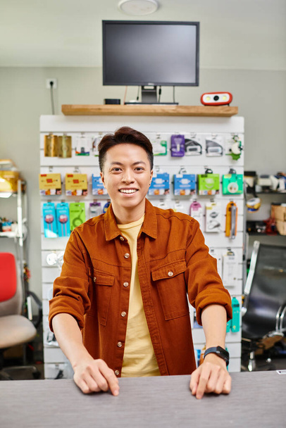 alegre asiático empresario mirando cámara en propia electrónica tienda, pequeño negocio concepto - Foto, imagen
