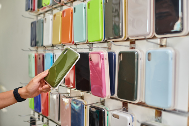 περικοπή άποψη του ανθρώπου κοντά βιτρίνα με διάφορα πολύχρωμα θήκες τηλέφωνο σε ιδιωτικό κατάστημα, μικρή επιχείρηση - Φωτογραφία, εικόνα