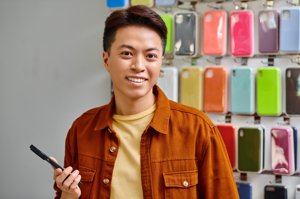 feliz asiático negocio holding smartphone y en cámara en privado electrónica tienda, pequeña empresa - Foto, imagen