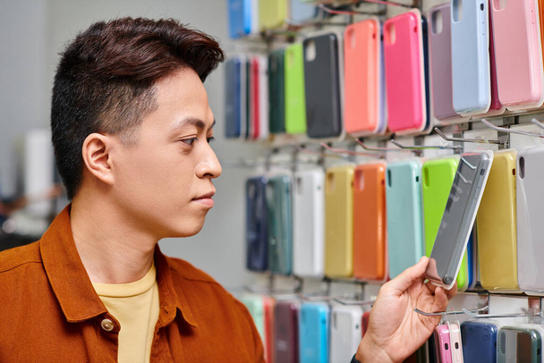 empresario asiático mirando colorido teléfono caso de escaparate de tienda privada, pequeña empresa - Foto, imagen