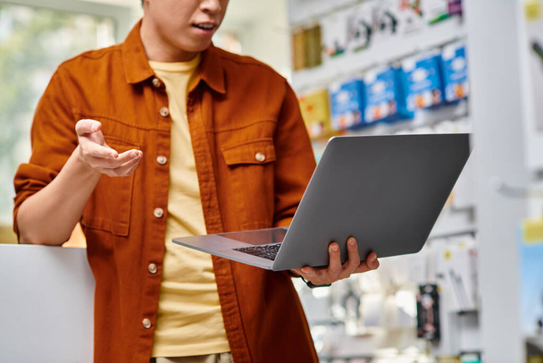 обрізаний вид бізнесмена жестикулюючи під час відеодзвінка на ноутбуці в приватному магазині електроніки - Фото, зображення