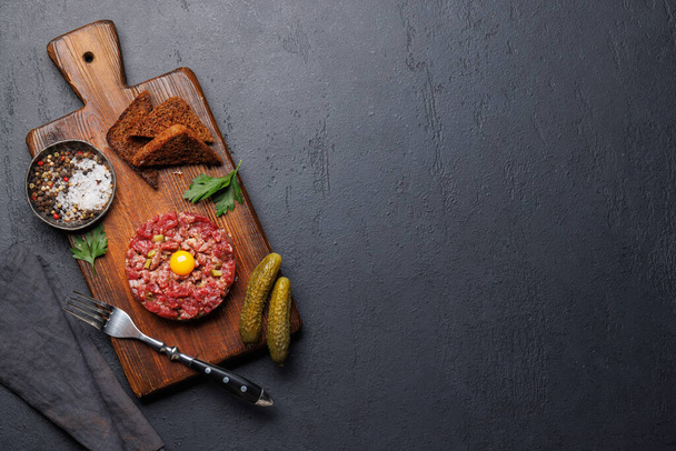 Savory beef tartare with pickled gherkins and brown bread toasts. Flat lay with copy space - Photo, Image